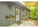 Close up of the front door and porch area featuring plants in containers and sconce lighting at 5848 Kingswood Ct, Norcross, GA 30093