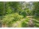 View of property with lush landscaping, mature trees, and driveway at 5848 Kingswood Ct, Norcross, GA 30093