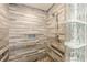 Detail of a tiled shower with grab bars, a glass block wall, and a shower head, highlighting accessibility and modern design at 5848 Kingswood Ct, Norcross, GA 30093
