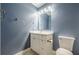 This bathroom includes a modern vanity, ample lighting, toilet, and elegant blue walls at 5868 Kingswood Nw Ct, Norcross, GA 30093