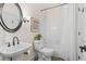 Cozy bathroom with round mirror, pedestal sink, and shower/tub combo with white tile at 121 Clipper Bay Drive, Alpharetta, GA 30005