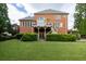 Backyard view of a two-story brick home featuring a deck, covered patio, well-manicured lawn, and mature trees at 1232 Everton Pl, Cumming, GA 30041
