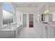 Luxurious bathroom with soaking tub, large window, double vanity, and marble countertops and floors at 1232 Everton Pl, Cumming, GA 30041