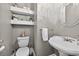 Stylish half-bathroom featuring a pedestal sink, round mirror, and decorative floating shelves at 1232 Everton Pl, Cumming, GA 30041
