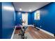 Bright blue exercise room with stationary bike, weights, and dark wood laminate flooring at 19 Autumn Ne Pl, White, GA 30184