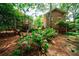 Lush backyard with mature trees, brick home, and deck with outdoor seating offers a serene and private setting at 27 S Avondale Rd, Avondale Estates, GA 30002