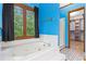 Corner bathtub next to a spacious, carpeted walk-in closet featuring built-in shelving at 200 Zachary Woods Nw Pt, Marietta, GA 30064