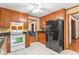 Well-lit kitchen featuring wooden cabinets, a black refrigerator, and white appliances at 200 Zachary Woods Nw Pt, Marietta, GA 30064
