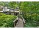 Unique exterior with a wooden walkway surrounded by lush greenery and mature trees at 285 Glen Lake Dr, Atlanta, GA 30327