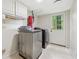 Well-lit laundry room with appliances, overhead cabinets and a door to the outside at 285 Glen Lake Dr, Atlanta, GA 30327