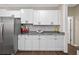 A modern kitchen features white cabinets, granite counters, stainless refrigerator, and gray backsplash at 338 Mount Zion Rd, Oxford, GA 30054