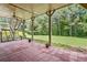 Red brick back patio with ceiling fan overlooking the lush backyard and stairs leading to an elevated deck at 601 Laurel Xing, Canton, GA 30114