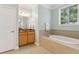 Bathroom with tile surround bathtub, vanity, cabinets, mirror and natural light from window at 601 Laurel Xing, Canton, GA 30114