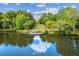 Scenic lake view, featuring a wooden dock and landscaped tiers leading up to a home nestled among mature trees under a blue sky at 601 Laurel Xing, Canton, GA 30114
