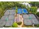 Aerial view of multiple well-maintained tennis courts with blue and green surfaces, surrounded by lush greenery and a tranquil lake at 601 Laurel Xing, Canton, GA 30114