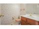 Small bathroom with floral wallpaper, oak vanity and wood toilet seat cover and matching hardware at 109 Lake Latimer Ne Cv, Kennesaw, GA 30144