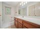Bathroom featuring a long vanity with a sink, large mirror, patterned wall paper, and tub with shower at 109 Lake Latimer Ne Cv, Kennesaw, GA 30144