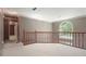 Upstairs landing with wood railing, a pendant light, and large arched window providing natural light at 109 Lake Latimer Ne Cv, Kennesaw, GA 30144