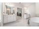Bright primary bathroom featuring dual vanities, a soaking tub, and an open doorway to the bedroom at 2 Whites Pond Rd, Moreland, GA 30259