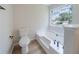 This bathroom features a soaking tub, toilet, and modern fixtures under a window at 5916 Farmbrook Ln, Rex, GA 30273