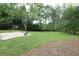 Expansive backyard featuring a concrete patio with two chairs, lush green grass, and an abundance of mature trees at 3852 Vinyard Ne Ct, Marietta, GA 30062