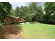 Home exterior displaying a lush backyard featuring mature trees, a manicured lawn, deck, and patio with comfortable seating at 3852 Vinyard Ne Ct, Marietta, GA 30062