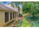The backyard features large windows, a door, and extensive greenery, including a stone path and lush ground cover at 4477 Village Dr, Atlanta, GA 30338