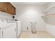 Functional laundry room with washer, dryer, overhead cabinet, and open shelves at 4477 Village Dr, Atlanta, GA 30338