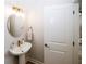 Modern bathroom with a pedestal sink, round mirror, and white door at 3579 Silvery Way, Powder Springs, GA 30127