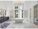 Bright bathroom with a soaking tub in front of large windows and a long vanity on the left at 1433 Wessyngton Ne Rd, Atlanta, GA 30306