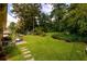 Lush backyard with a well-manicured lawn, mature trees, and a stone pathway at 1472 High Meadow Dr, Stone Mountain, GA 30083