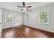 Sunny bedroom featuring hardwood floors, two windows, and a ceiling fan for comfort and style at 1913 Ferry Dr, Marietta, GA 30066