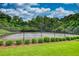 Community tennis court surrounded by a black fence, with manicured bushes lining the court at 556 Walton Dr, Social Circle, GA 30025