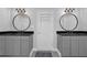 Dual vanities with black countertops and round mirrors in a brightly lit bathroom at 3992 Spot Rd, Cumming, GA 30040