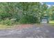 Exterior view of a property with garage, outbuilding and ample parking surrounded by mature trees at 3992 Spot Rd, Cumming, GA 30040