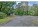 Exterior view of a property with an outbuilding, storage and ample parking surrounded by mature trees at 3992 Spot Rd, Cumming, GA 30040