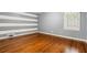 Empty bedroom with wood floors, striped wall, and window providing natural light at 5114 N Ivy Ne Rd, Atlanta, GA 30342