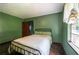 Bedroom with green walls, a metal bed frame, and dark, wood-stained flooring at 3020 Washington Rd, East Point, GA 30344