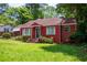 Delightful red brick bungalow with a covered entrance, manicured bushes, and a vibrant green lawn at 3020 Washington Rd, East Point, GA 30344