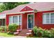Detailed shot of the red brick house's front entrance, showcasing the ornate door and trimmed shrubs at 3020 Washington Rd, East Point, GA 30344