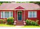 Focus on the front entrance of this charming red brick home, highlighting the unique door design and green lawn at 3020 Washington Rd, East Point, GA 30344