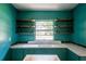 Charming laundry room featuring teal colored cabinetry, floating shelves, and vintage sink at 3020 Washington Rd, East Point, GA 30344