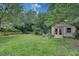 Spacious backyard with lush green grass and a charming shed surrounded by mature trees and a wood fence at 1131 Forrest Blvd, Decatur, GA 30030