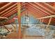 View of the unfinished attic area featuring wood beams, insulation, and single window providing natural light at 3358 Lake Dr, Lawrenceville, GA 30044