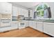 Bright kitchen featuring white cabinets, matching appliances, and wood floors at 3358 Lake Dr, Lawrenceville, GA 30044