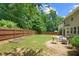 Lush backyard with a fire pit and gravel, surrounded by a wooden fence and mature trees at 4020 New Salem Ct, Cumming, GA 30040