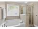 A stylish bathroom featuring a soaking tub under a window and a glass-enclosed shower with tile surround at 4020 New Salem Ct, Cumming, GA 30040