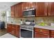 Close-up showcasing a stainless steel range, microwave, and light countertops, complemented by cherry wood cabinets and tiled backsplash at 4020 New Salem Ct, Cumming, GA 30040