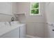 Functional laundry room with white washer and dryer, a small window, and built-in shelving for storage at 4020 New Salem Ct, Cumming, GA 30040