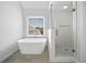 Bright bathroom showcasing a luxurious soaking tub and frameless glass shower with tile surround and window at 200 Glen Wood Place, Canton, GA 30114